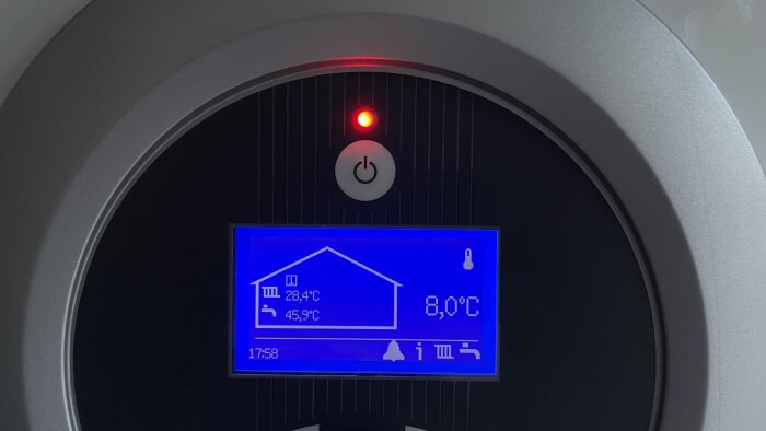 Digital display visar temperatur inomhus och utomhus med tidsangivelse, röd signal ovanför.