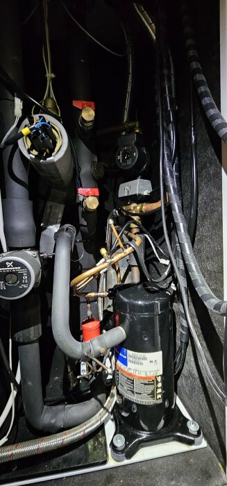 Komplex rörsystem och elledningar, pump och tekniska komponenter, möjligen en del av ett fartyg eller maskineri.