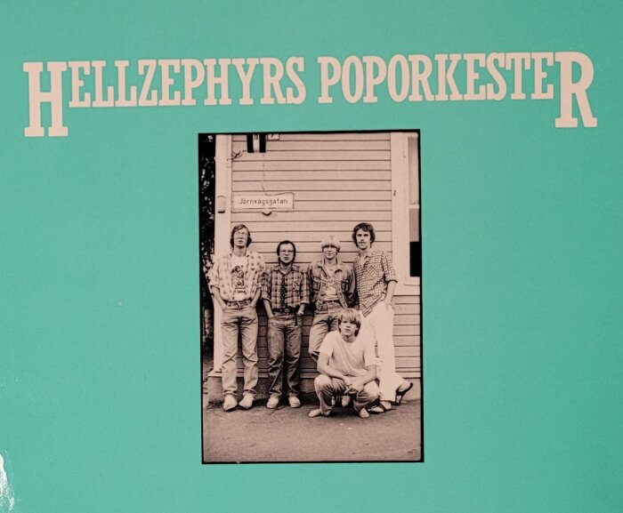 Fyra män framför byggnad, svartvitt foto, text "Hellzephyrs Poporkester", retrostil, album- eller bokomslag.