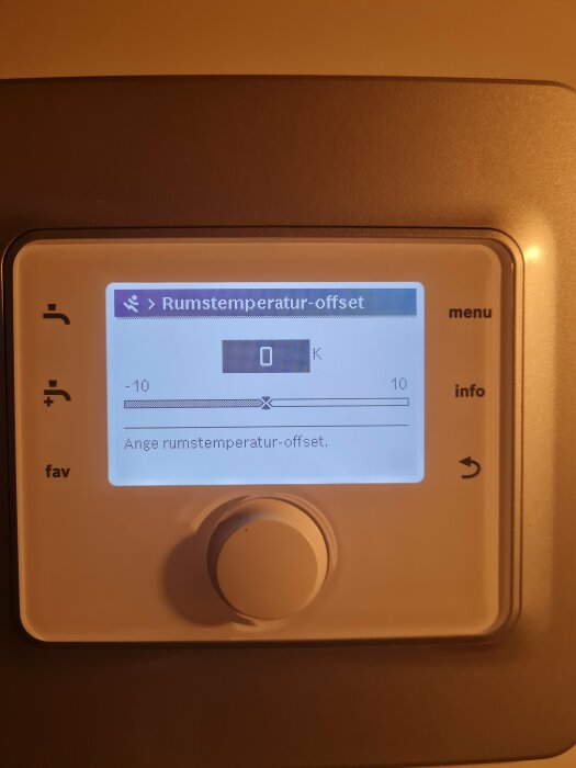 Digital termostat med display visar rumstemperatur-offset inställning i en skala från -10 till +10 Kelvin.