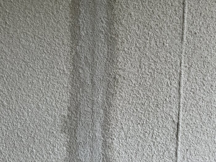 En grå, texturerad betongvägg med synliga fogskarvar. Minimalistisk och grov yta.
