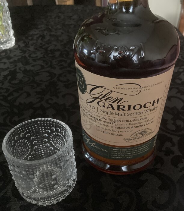 Flaska Glen Garioch whisky och texturerat glas på mönstrad bordduk.