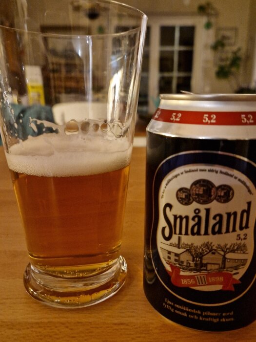 Ett glas öl bredvid en burk med texten "Småland", avbildande tradition och dryck.