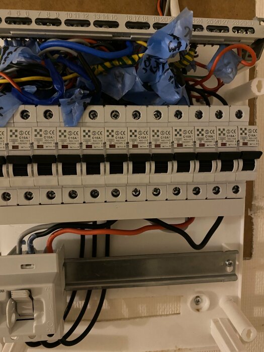 Elcentral med säkringar, isolerband, ledningar och strömbrytare, otillslutet skåp under installation eller service.