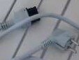 Ethernetkabel med RJ45-kontakter, grå, trasslig, liggande på en yta med skuggor.