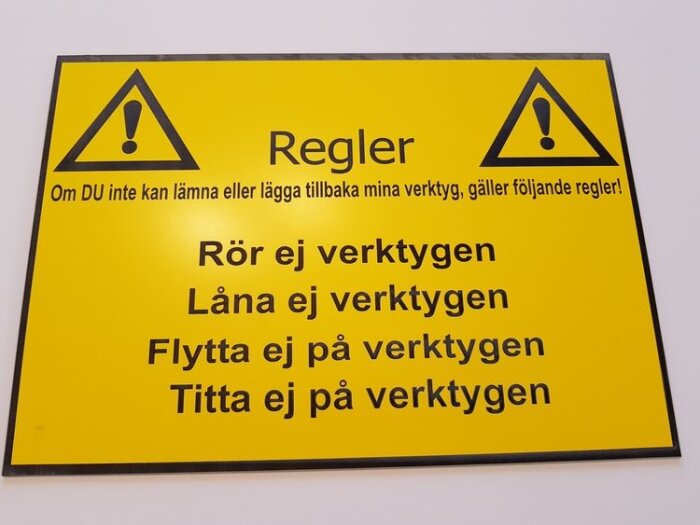 Gul skylt med varningstriangel och regler om att inte röra, låna, flytta eller titta på verktygen.