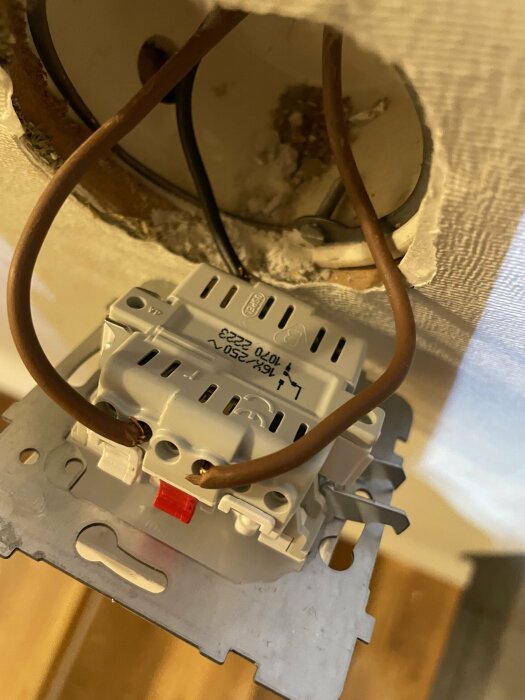 Installation av eluttag, osäkra kablar utan täckplatta, risk för elfara, oavslutat elarbete, väntar på färdigställande.