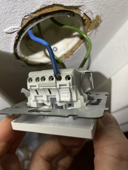 Installationsprocess av vägguttag med exponerade kablar och öppen väggdosering. Handhållen. Elektriskt arbete.