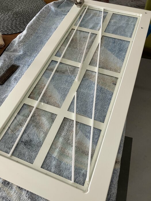 Vitt fönster på blått handduk, liggande på ett bord, under renovering eller reparation.