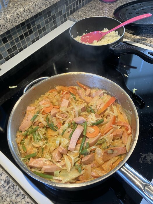 Stekpanna med grönsaker och kött på spis, gryta med ris, köksinredning, matlagning.