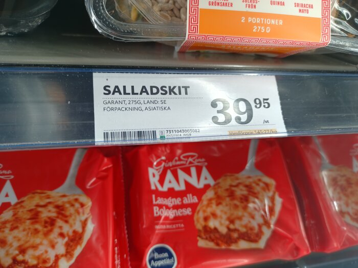 Salladskit pris 39,95, förpackad asiatisk sallad, varubeteckning i butikshylla, röd förpackning av lasagne nedanför.