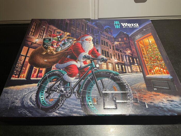 Adventskalender med jultema, verktyg, jultomten på cykel, gåvor, snö, kväll, målade illustrationer, numrerade luckor.