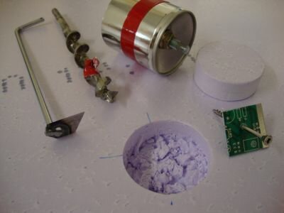 Laboratoriematerial och komponenter, möjligtvis för kemiskt eller fysiskt experiment, med pulver och elektronikdel.