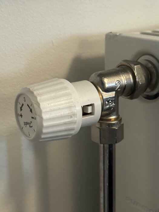 Termostatventil på en radiator, numrerad reglageinställning, energisparande, väggmonterad, inomhus.