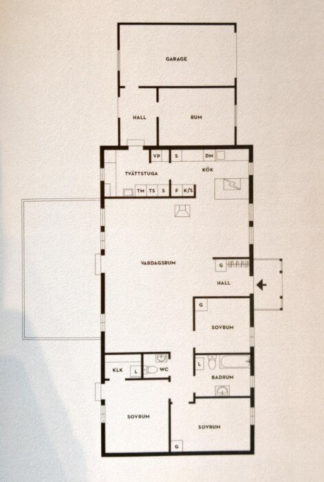 Arkitektonisk ritning av ett hus med etiketterade rum som kök, sovrum, badrum, vardagsrum och garage.