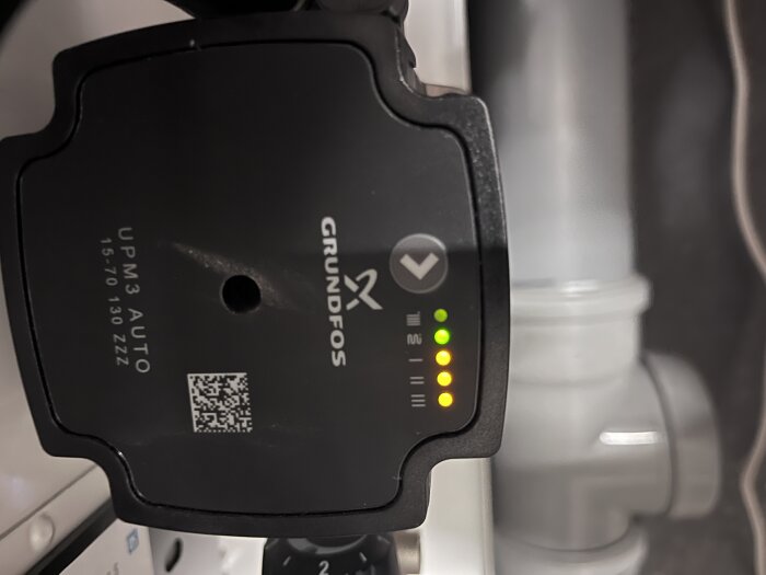 Grundfos varumärke, pumpmekanism, gröna lysdioder, QR-kod, industriell utrustning, otydlig bakgrund.