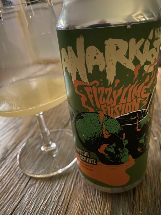 Ölburk med texten "NARKOSA Fizzy Lime", halvfyllt vinglas, träbord i bakgrunden.