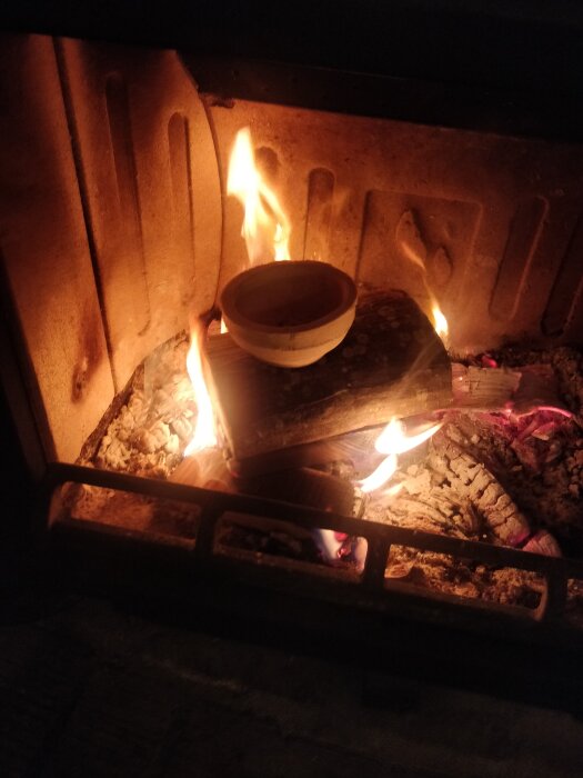Kopp i öppen spis med brinnande ved, skapar en mysig och varm atmosfär.