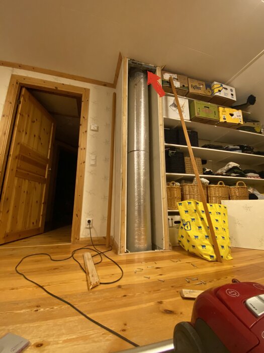 Inomhusmiljö under renovering med synlig isolering, byggmaterial, eluttag och golvavfall.