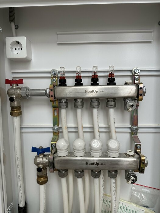 Ett värmesystem med rör, ventiler och kopplingar monterat på en vägg.