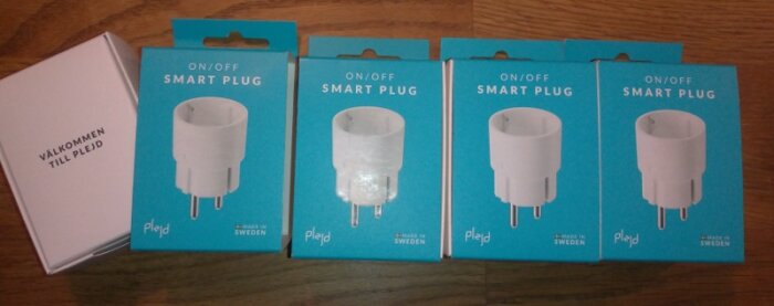 Fyra smarta pluggar i förpackning och en vit låda på träyta.