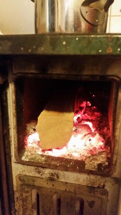 Brinnande ved i en öppen gammal kamin, rostig, varmt ljus, hemtrevligt, enkel uppvärmningsmetod.