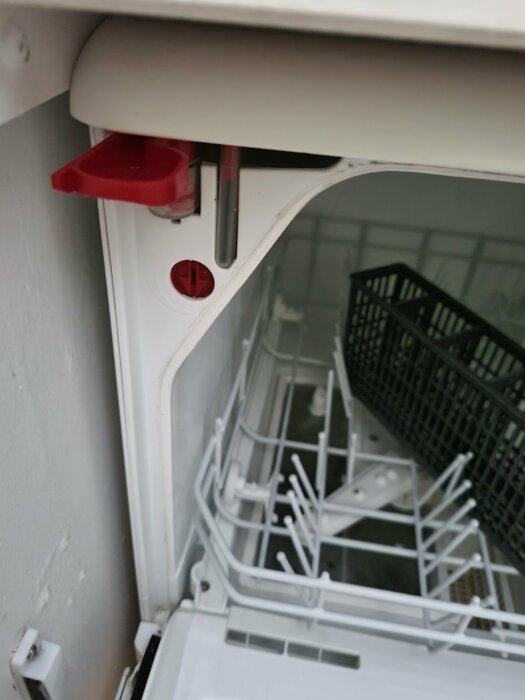 Inre del av öppen diskmaskin med synliga diskkorgar och spolarm; röda detaljer och reglage synliga.