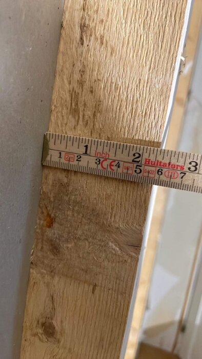 Måttband mot träyta, mäter dimension, arbetsmiljö, byggnad, hantverk, precision, husrenovering, cirka 5 cm synligt.