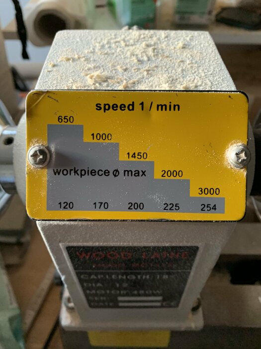 Skylt på maskin med hastigheter och arbetsstyckets maxdiameter, dammigt, industriellt.