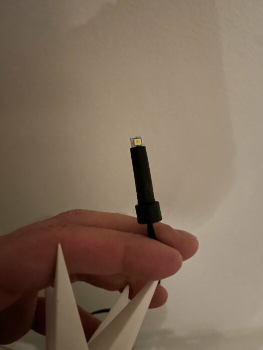 En hand håller en USB-C-kabel och ett vitt papper.