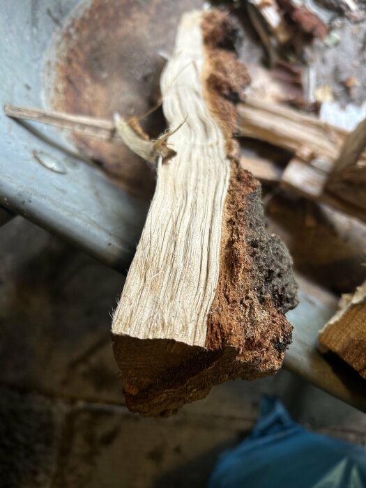 Ett stycke trä med varierande textur och färg, möjligen angripet av röta eller termiter, inomhus.