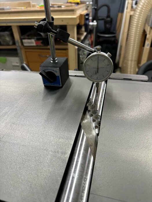 Urmätare monterad på magnetisk bas mäter metallstångs precision i verkstadsmiljö.