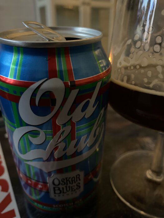 Öppnad ölburk, oskarp bakgrund, glas med mörkt öl, Oskar Blues bryggeri, livsstil, närbild.