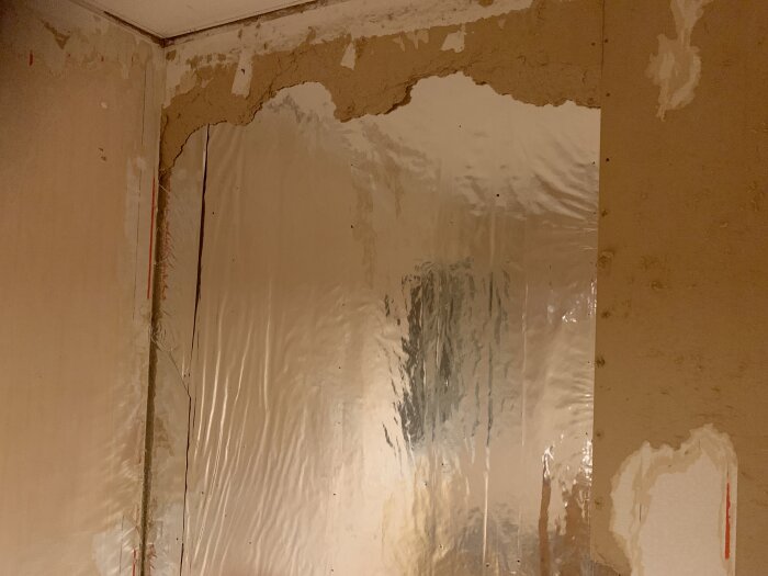 Rum under renovering med spacklade väggar och plastöverdrag. Obearbetad och ofärdig inredning.