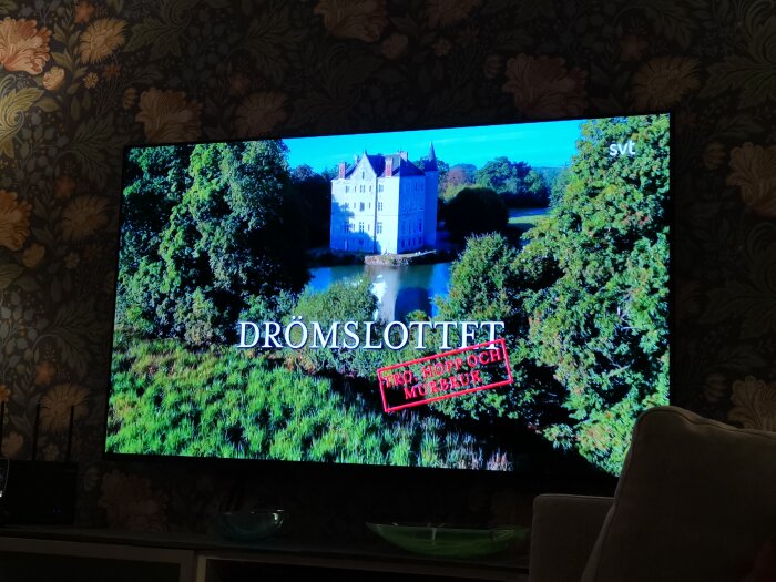 En TV-skärm visar programmets titel "Drömslottet" från SVT med ett slott omgivet av grönska.