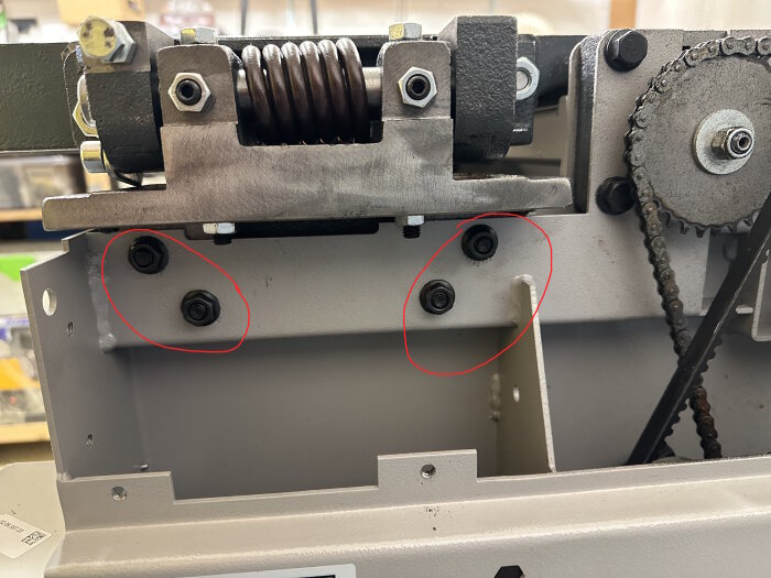 Industriell utrustning med fjädrar, kedjor och bultar, markerade områden antyder fokus på specifika detaljer.