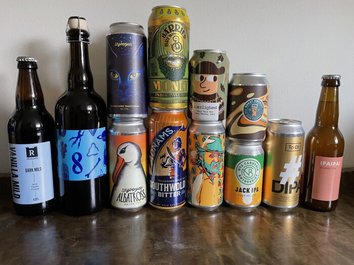 Samling av olika ölflaskor och -burkar med unika etiketter på en yta.