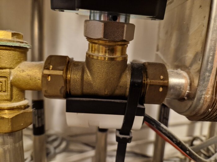 VVS-installation: kopparledningar, backventil, anslutningar och regleringsutrustning i förgrunden.