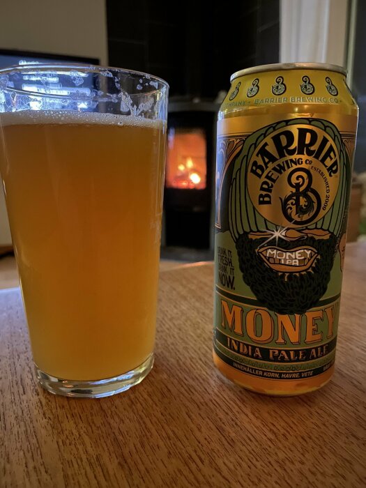 Ett glas öl bredvid en IPA ölburk med eldstad i bakgrunden.