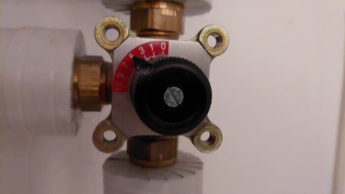 Radiatorventil med termostat, temperaturskala, mässingsdetaljer, plast, vägg, VVS-installation.