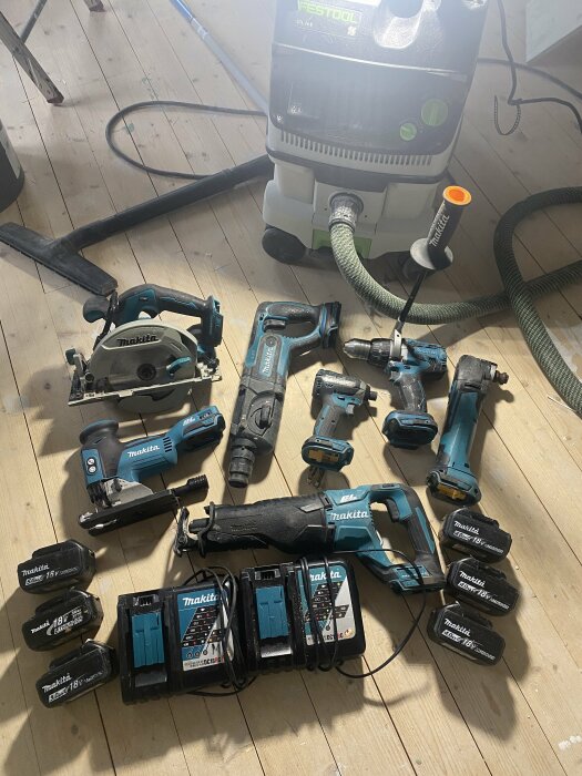 Verktyg och utrustning för byggarbete utspridda på ett trägolv. Makita och Festool märken synliga.