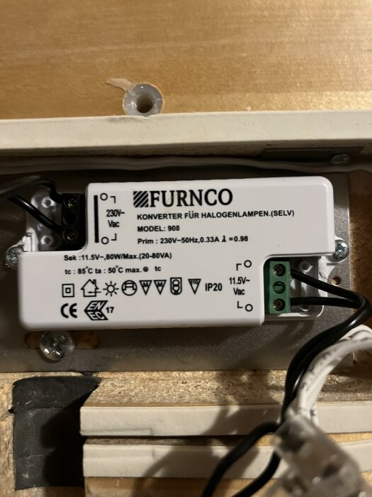 Elektronisk transformator för halogenlampor, monterad på trä, med tekniska specifikationer och ledningar synliga.