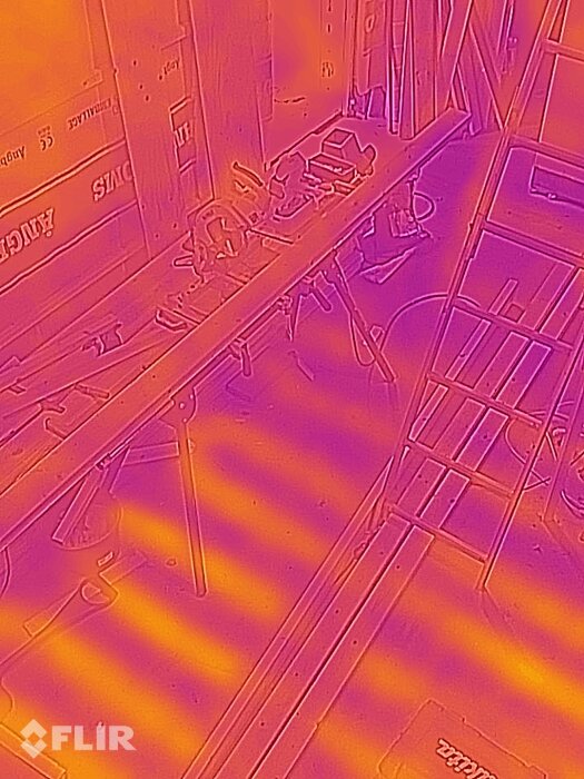 Termisk kamera bild av ett rum med objekt och stege, färggradienter indikerar temperaturskillnader.