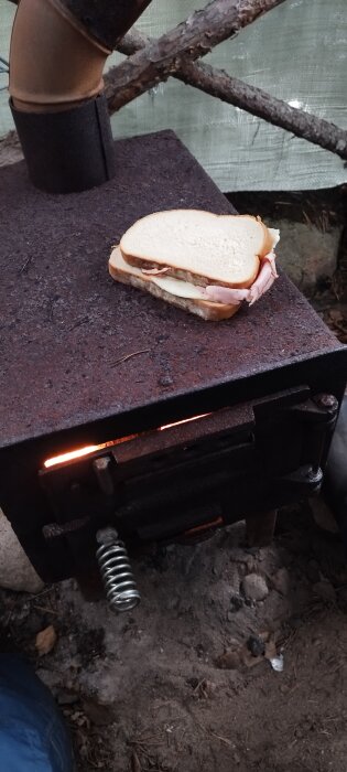Macka på bärbar utomhusgrill med tänd kol, naturbakgrund, grillningsäventyr, rustik matlagning.