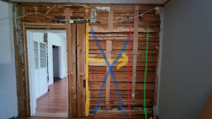 Renovering av rum, träväggar synliga, elledningar, färgad tejp markerar, ingen gips eller inredning.