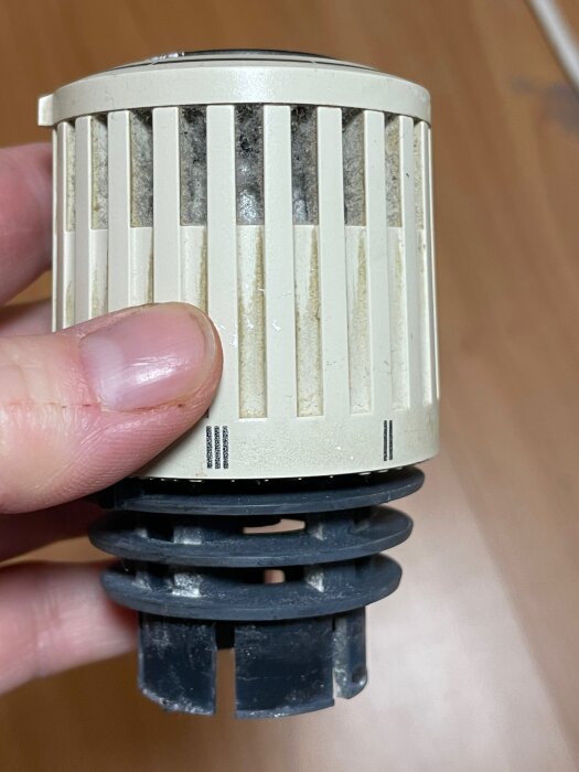 Använd hand håller smutsig termostatventil för radiator. Renoveringsbehov synliga. Fokus på damm och slitage.