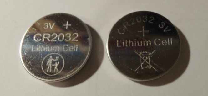 Två CR2032 3V litiumknappcellsbatterier, ett med slitage, säkerhetsvarningssymboler.
