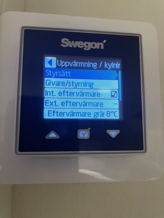 LCD-display visar meny från Swegon klimatsystem. Uppvärmning/kylning, sensorer och eftervärmare val är synliga.