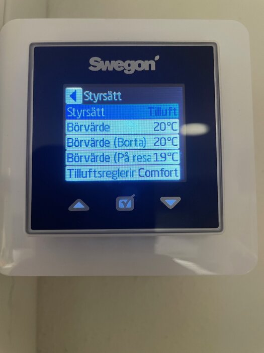 Digital termostat med LCD-skärm, visar temperaturinställningar, märkt "Swegon", väggmonterad.