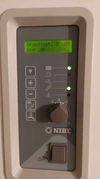 Värmepumpens styrenhet med LCD-skärm och justeringsknappar; varningslågor tända; NIBE-logotypen synlig.